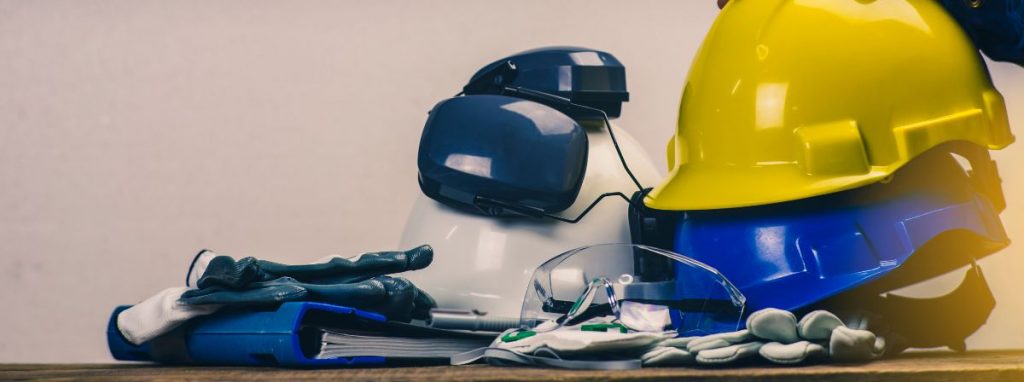 Caschi di sicurezza, occhiali protettivi, guanti e documentazione per la sicurezza sul lavoro, simboli dell'incarico RSPP e della redazione del DVR.